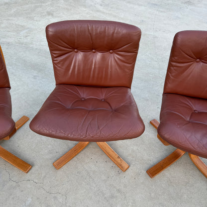 A Rare Set of 4 Vintage Joe Rufenacht Lounge Chairs in Howe leather, with tufted seats, wooden X-shaped bases, and Scandinavian design, sits on a concrete surface beside two matching chairs partially visible.