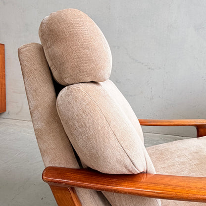 A close-up side view of the Vintage Mid Century Tessa T21 Swivel Chair (Revive) in cream velvet with wooden armrests, thick cushioned headrest and backrest, highlights its timeless mid-century style against a plain light-colored wall.