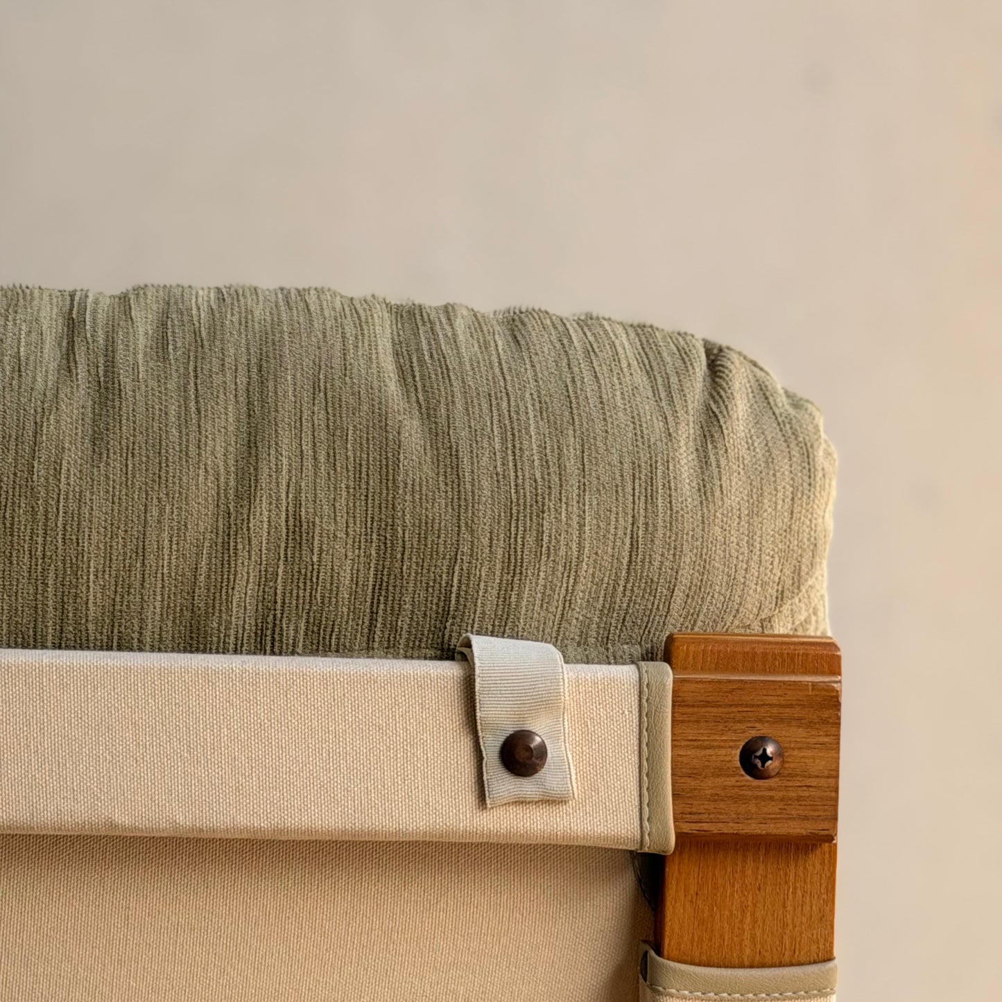 Close-up of a Tessa Monaco Arm Chair from the Pair of Tessa Monaco Arm Chairs - Sage Green Corduroy Like New (Revive), showing its sage green corduroy cushion and materials, with a neutral background emphasizing its mid-century design.