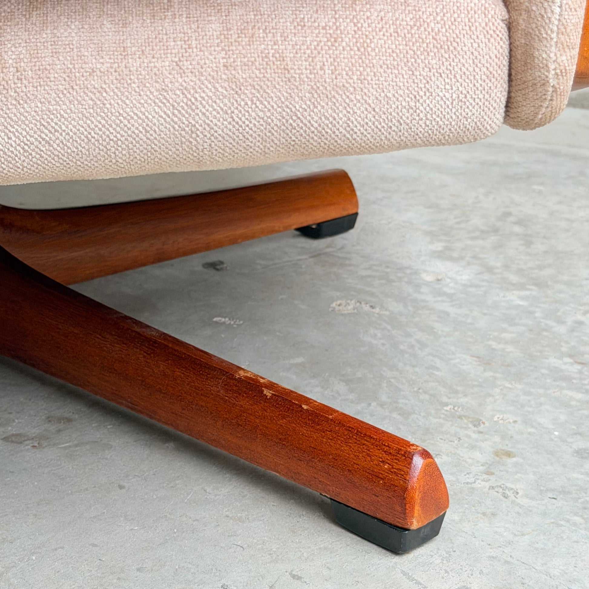Close-up of a cream velvet Vintage Mid Century Tessa T21 Swivel Chair (Revive) with polished wooden leg and black plastic foot on a textured light gray floor, showcasing classic mid-century style.