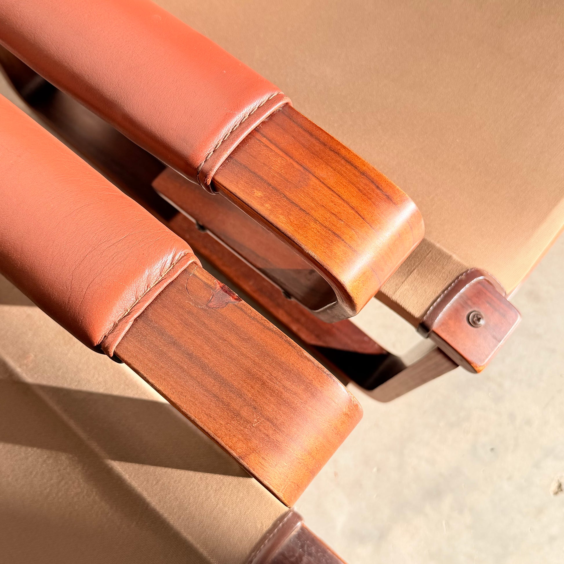Close-up of two wooden armrests with tan leather upholstery and visible stitching on beige fabric chairs, bathed in sunlight—a classic mid-century modern look inspired by the Tessa T8 Lounge Suite modular two-seater sofa & armchairs (Revive).