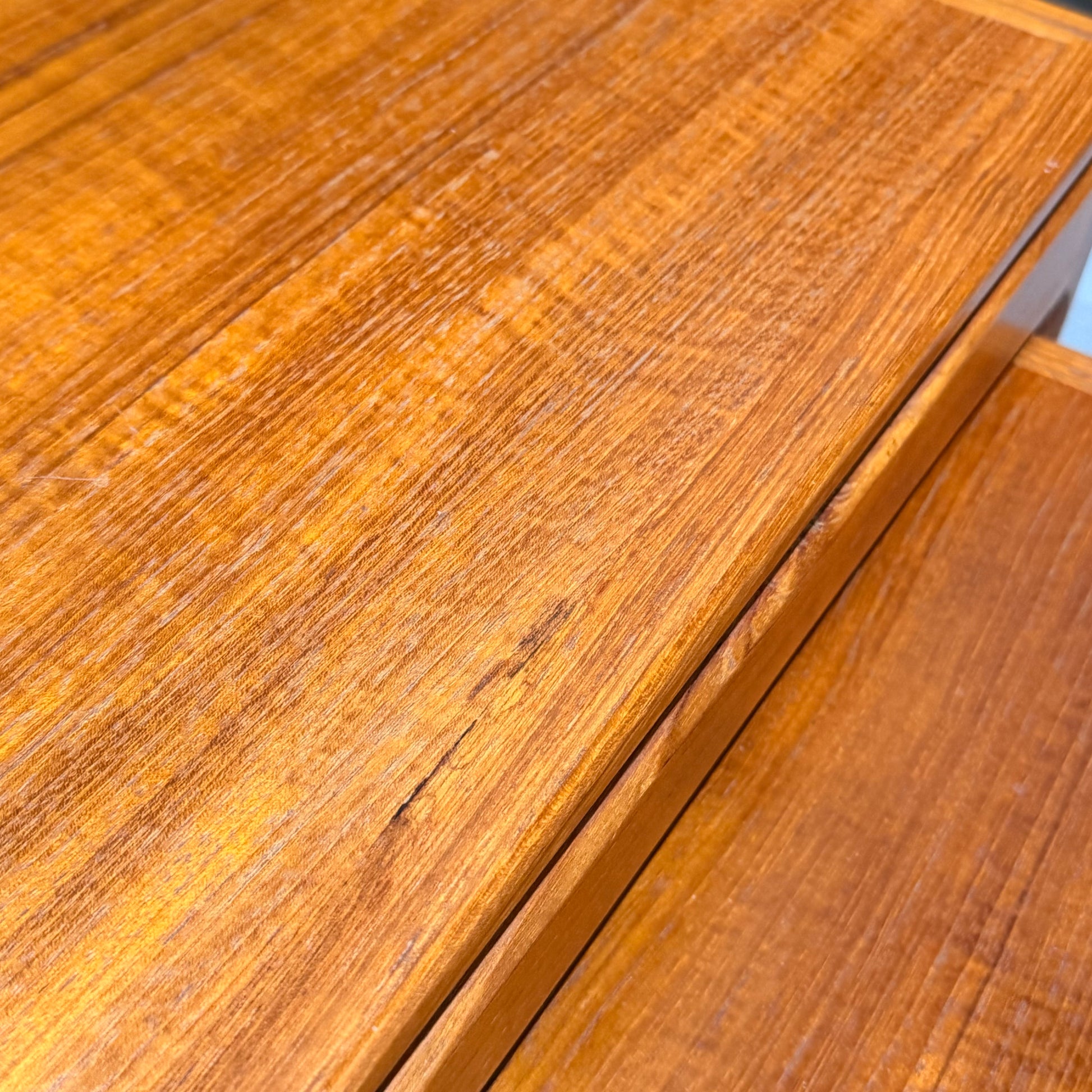 Close-up of a Rare set of Alpa Teak Nesting Tables – Set of 3, Australian Mid-Century Modern. Warm golden-brown finish with visible wood grain; one table has a noticeable scratch across the top surface.