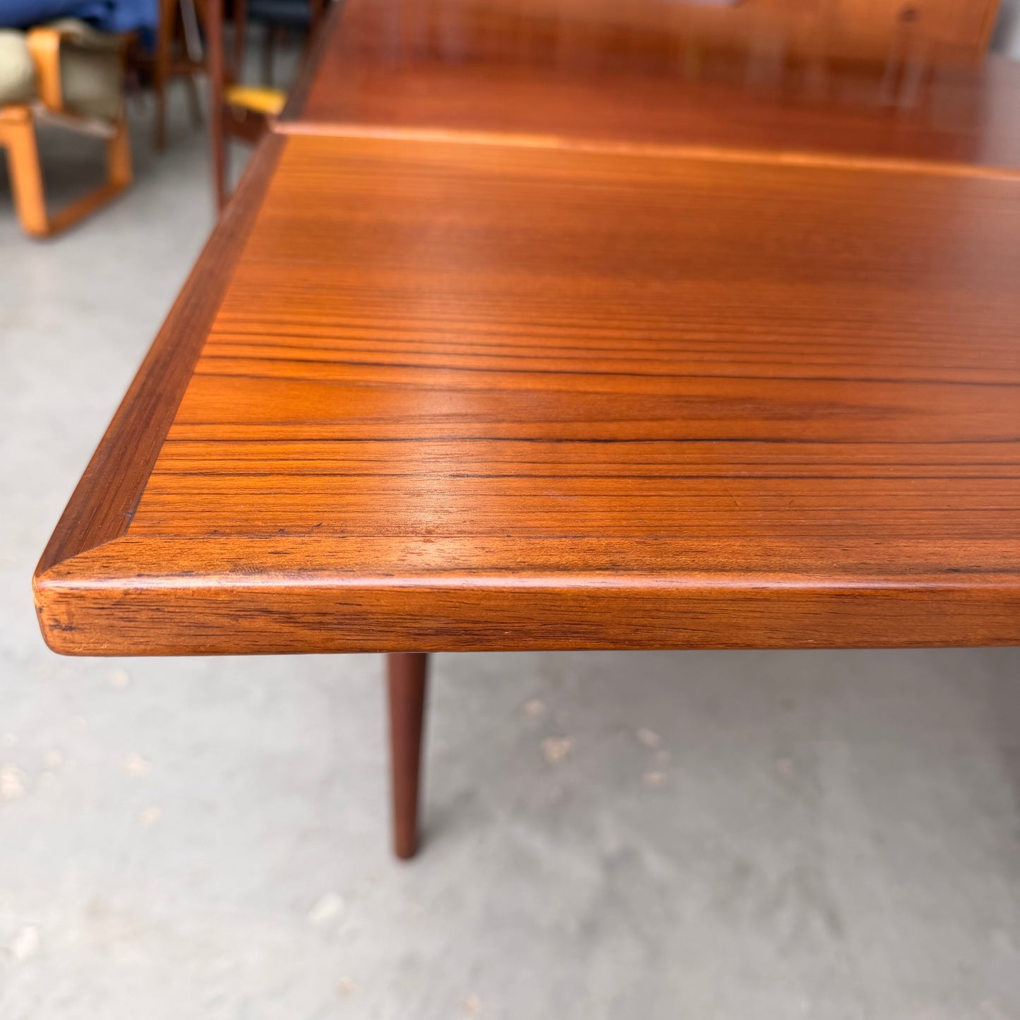 A close-up of the Vintage Mid-Century Parker 109 Nordic Extension Dining Table – Table Only (Revive), showing its warm, polished finish and smooth wood grain on a light-colored concrete floor.