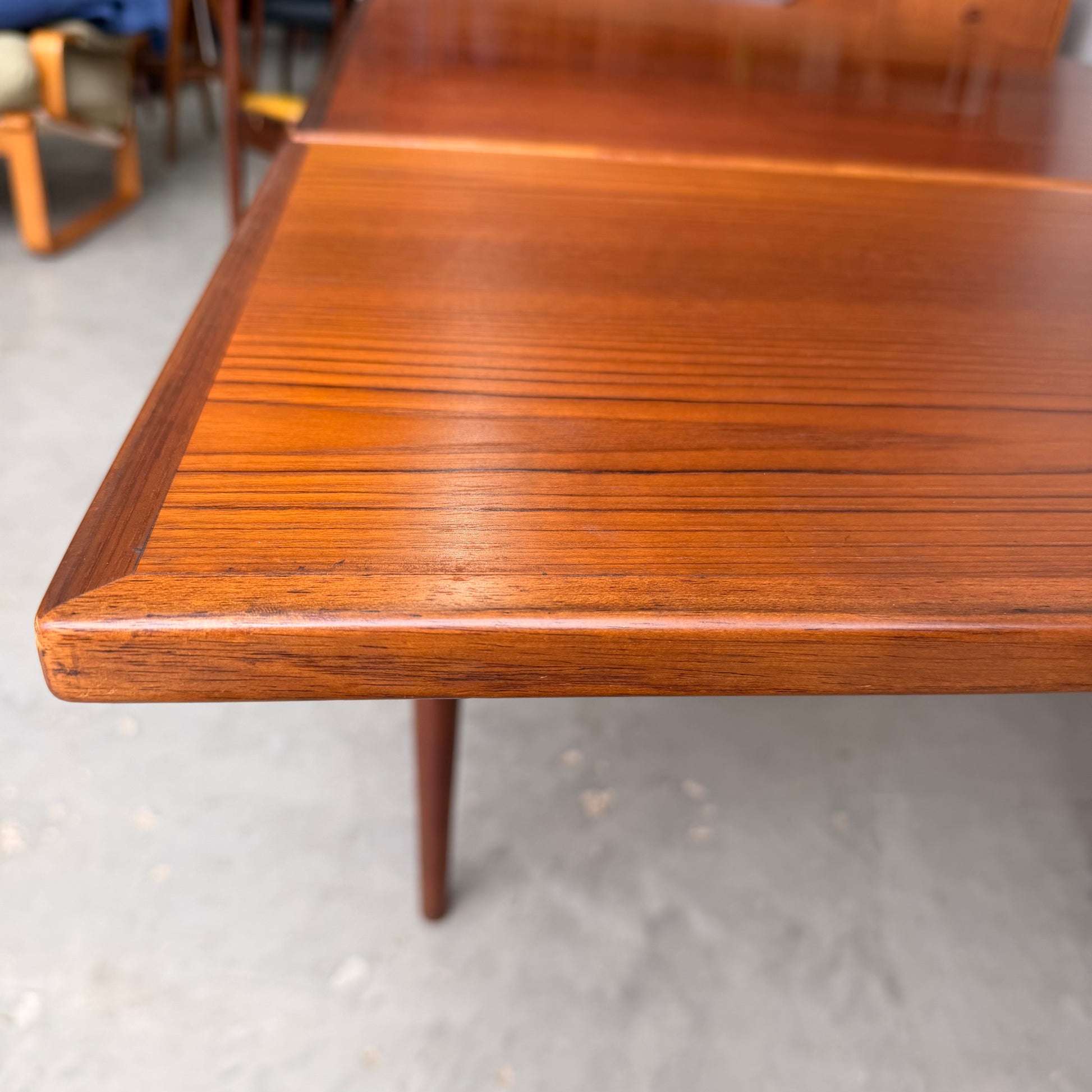 A close-up of the Vintage Mid-Century Parker 109 Nordic Extension Dining Table – Table Only (Revive), showing its warm, polished finish and smooth wood grain on a light-colored concrete floor.