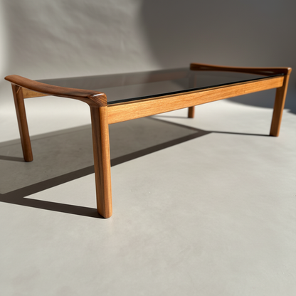 The Tessa TC 21 Coffee Table Frame Restored - (Revive) features a rectangular glass top and restored wood frame, displayed in natural light. Its modern minimalist design embodies classic mid-century style.