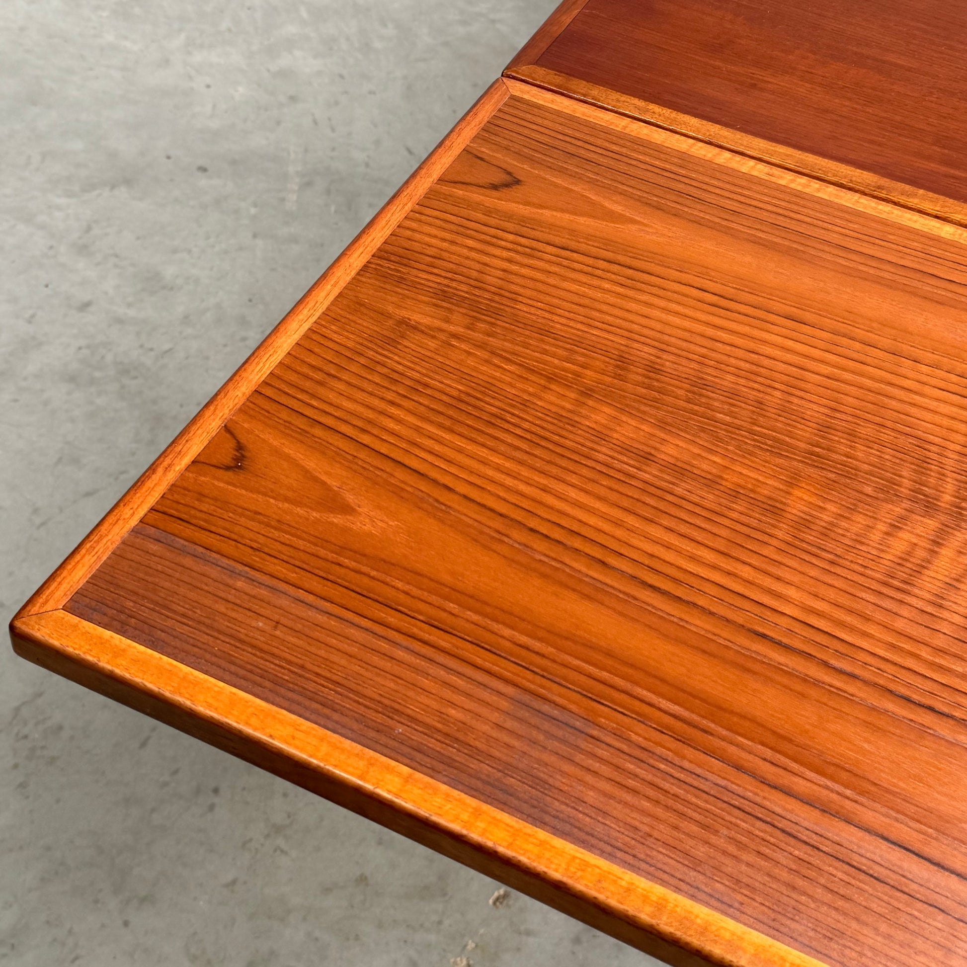 Close-up of the Vintage Mid-Century Parker 109 Nordic Extension Dining Table (Revive), highlighting its rich, warm finish, visible natural wood grain, and smooth surface against a plain light-colored floor. Table only.