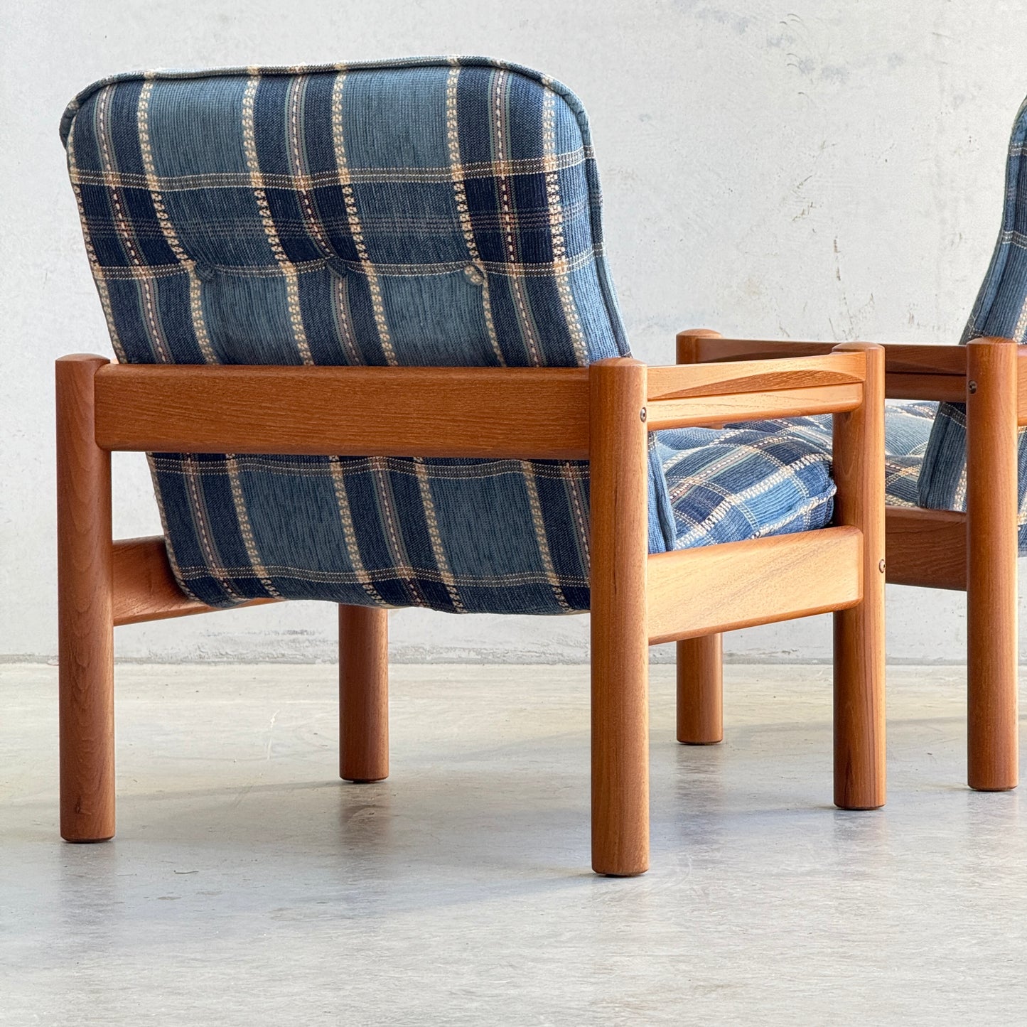 The Restored Domino Møbler Armchairs – Blue Plaid Mid-Century Set (Rediscover) features solid wood frames and retro blue plaid cushions, bringing timeless Scandinavian style to any space with their iconic mid-century modern design.