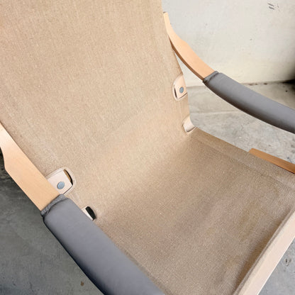 A close-up of a Pair of Tessa Ferrara Swivel Armchairs (Revive) with beige fabric, light wooden armrests, and grey covers on a concrete floor by a pale wall—highlighting classic mid-century Australian design.