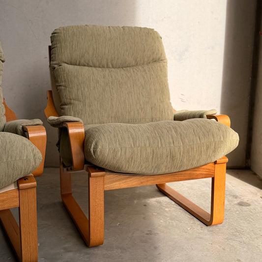 A pair of Tessa Monaco Arm Chairs in sage green corduroy, like new (Revive), with light wooden frames sits on a concrete floor in sunlight; one chair is fully visible, the other partially shown on the left.