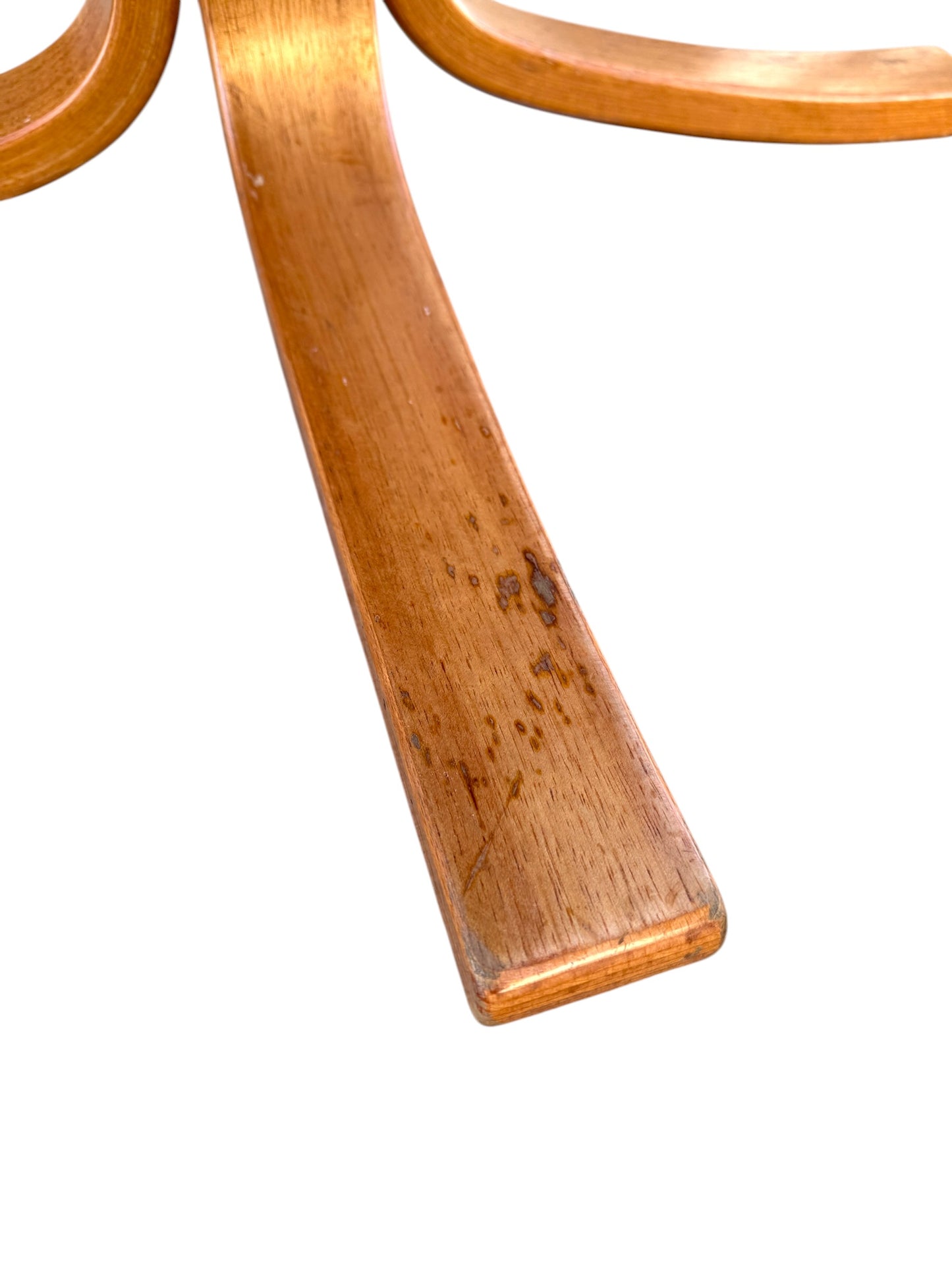 Close-up of a curved, light brown wooden leg with visible grain and minor marks, from a Rare Set of 4 Vintage Joe Rufenacht Lounge Chairs – Howe Leather, showcasing Scandinavian design against a white background.