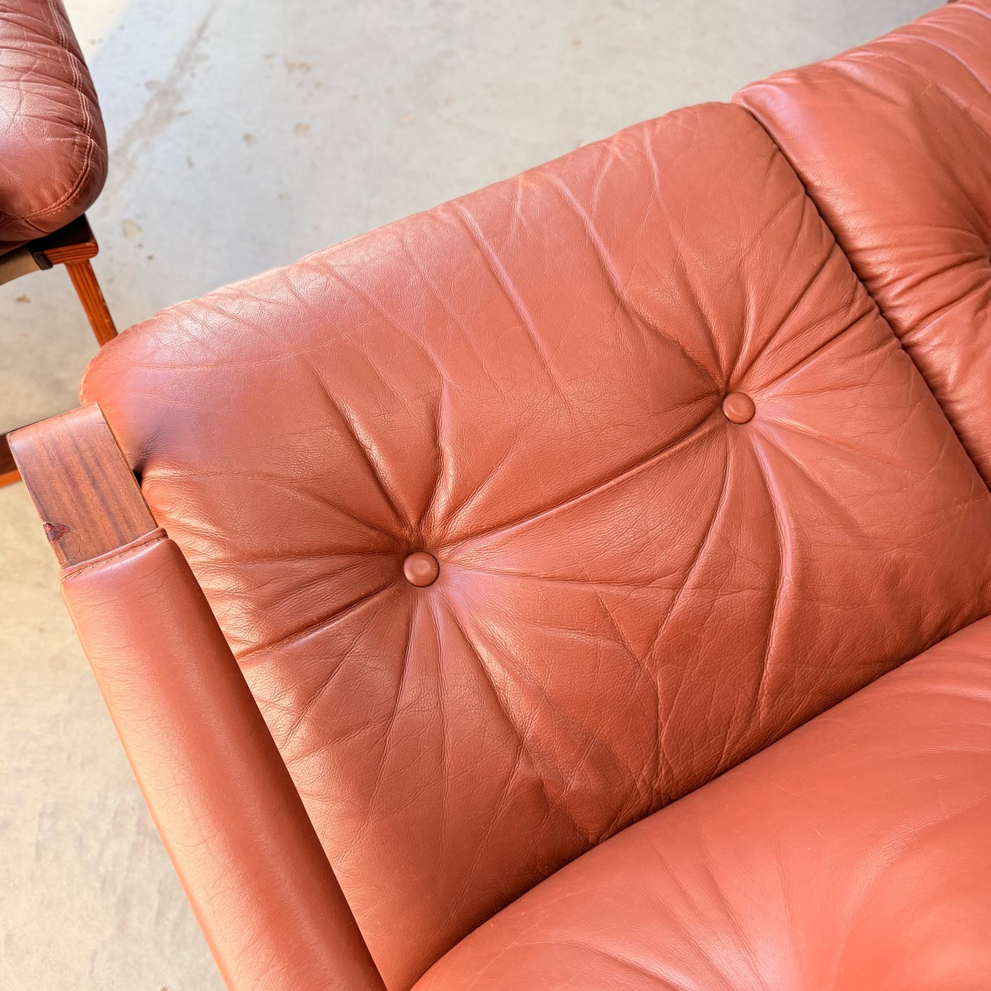 Close-up of a vintage reddish-brown tufted leather Tessa T8 Lounge Suite (Revive) modular two-seater sofa & armchairs, showcasing mid-century modern style with visible creases and button details.