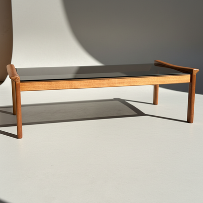 Featuring a modern minimalist design, the Tessa TC 21 Coffee Table Frame Restored – (Revive) has a rectangular black glass top and restored wooden frame, set on a light surface with a gentle side-cast shadow.