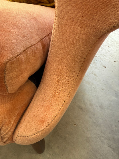 Close-up of a Mid-Century High-Back Wingback Armchair in dusty pink velvet with blackwood frame, showing some wear on the armrest; set on a concrete floor. Priced individually.