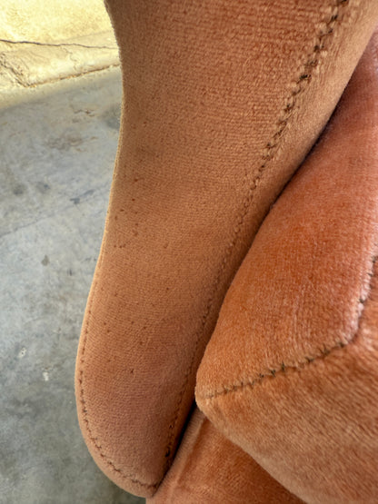 Close-up of a Mid-Century High-Back Wingback Armchair in dusty pink velvet with blackwood frame, priced individually (Rediscover). Visible stitching and slightly worn fabric evoke vintage charm. Concrete floor and wall in the background.