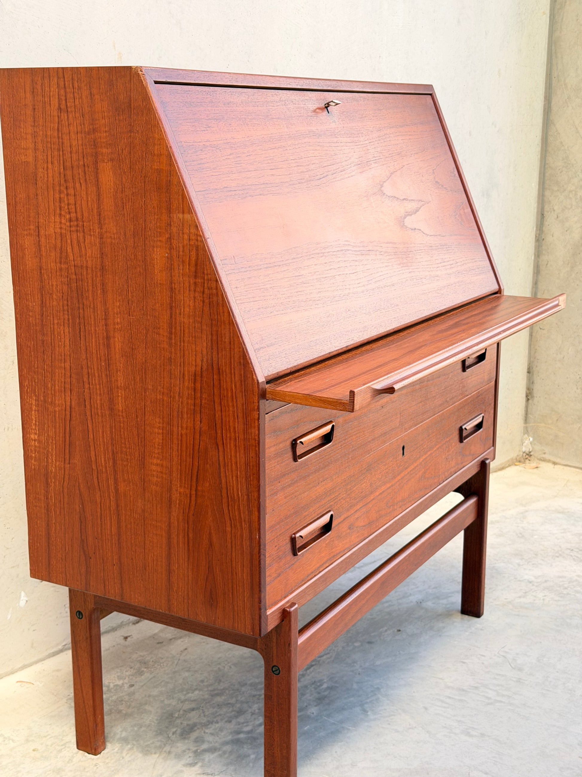 The Mid Century Modern Danish Arne Wahl Iversen Model 68 Teak Secretary Desk by Vinde Møbelfabrik features an angled top, fold-down writing surface, rectangular-handled drawers, and slender legs—an elegant nod to vintage design.