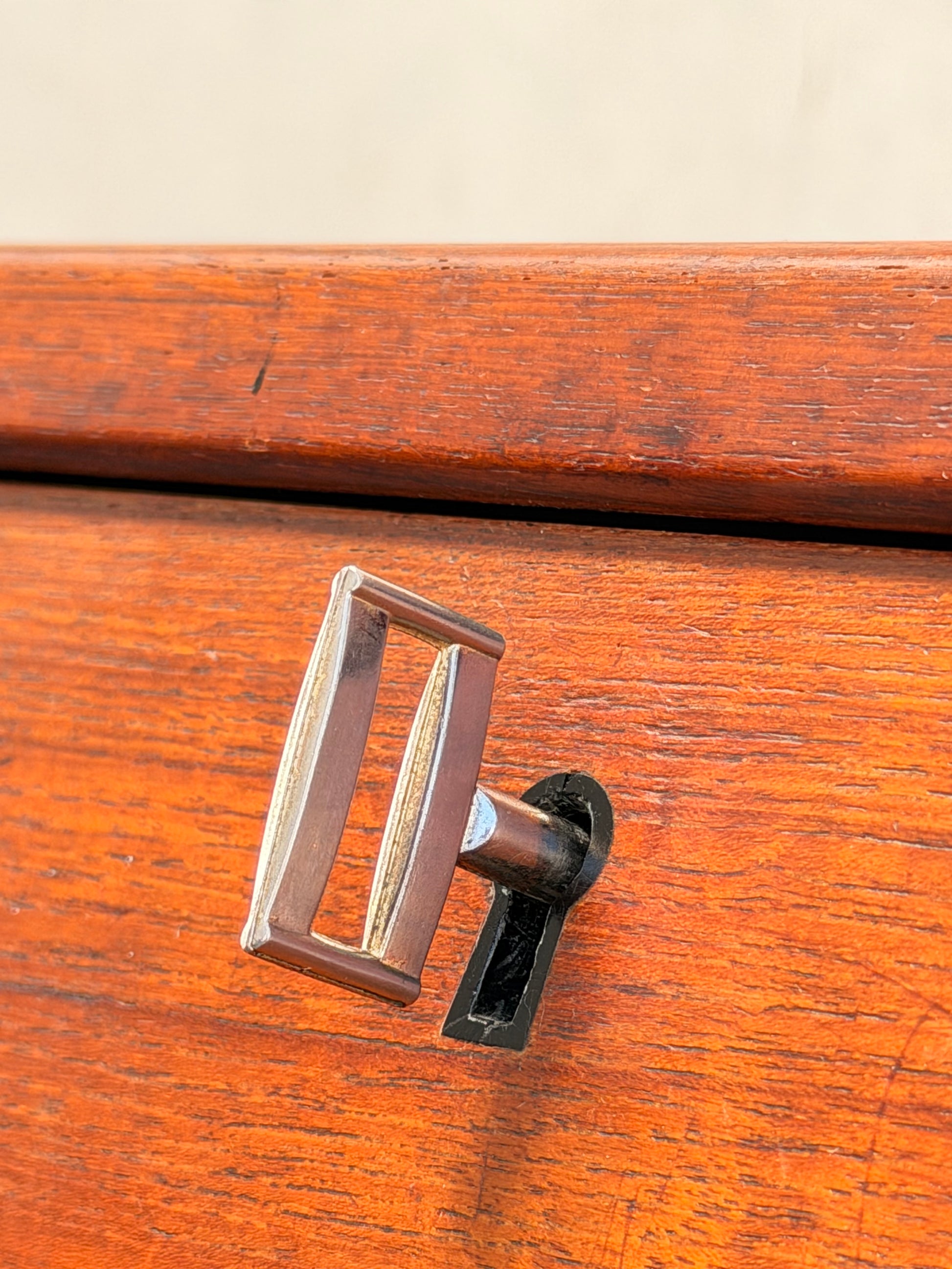 A close-up of an old-fashioned barrel key in the keyhole of a Mid Century Modern Danish Arne Wahl Iversen Model 68 Teak Secretary Desk by Vinde Møbelfabrik highlights its classic brass finish and rich wood grain.