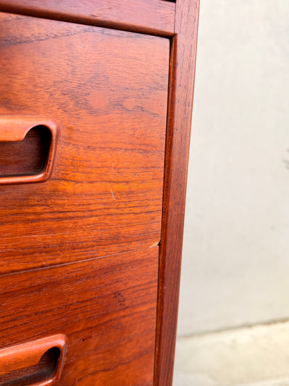 Close-up of a Mid Century Modern Danish Arne Wahl Iversen Model 68 Teak Secretary Desk by Vinde Møbelfabrik, showing two handles, a small chip on the middle drawer edge, and set against a light wall and floor.