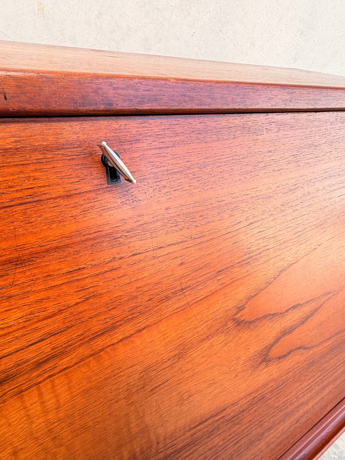 Close-up of the Mid Century Modern Danish Arne Wahl Iversen Model 68 Teak Secretary Desk by Vinde Møbelfabrik, highlighting its rich teak grain and a small metal key inserted in the top left lock.