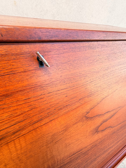 Close-up of the Mid Century Modern Danish Arne Wahl Iversen Model 68 Teak Secretary Desk by Vinde Møbelfabrik, highlighting its rich teak grain and a small metal key inserted in the top left lock.