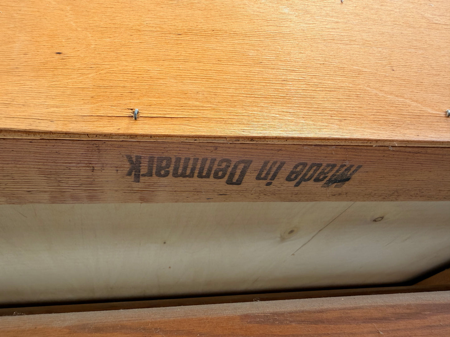 A fly rests on wood above an upside-down "Made in Denmark" mark, echoing the timeless mid-century style of the Arne Wahl Iversen Model 68 Teak Secretary Desk by Vinde Møbelfabrik.