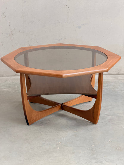 An octagonal hardwood Kalmar Furniture coffee table with smoked glass top and integrated magazine rack (Revive), set against a concrete backdrop—an elegant statement of mid-century modern Australian design.