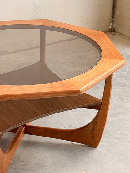 The Octagonal Mid Century Coffee Table by Kalmar Furniture features a hardwood frame, smoked glass top, and built-in magazine rack—a striking blend of wood and glass in Australian design, perfect for modern interiors.