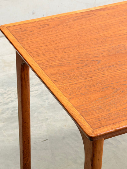 Close-up of the corner of a Classic Australian-Made Noblett Mid-Century Teak Nesting Table (Circa 1970s, Revive), featuring tapered legs and smooth teak grain inspired by Scandinavian design, standing on a light-colored floor.