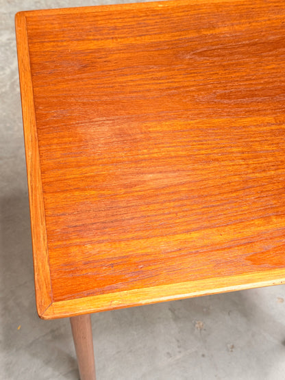 A close-up of the Classic Australian-Made Noblett Mid-Century Teak Nesting Tables – Circa 1970s (Revive), highlighting the corner and surface, set against a plain, light-colored floor.