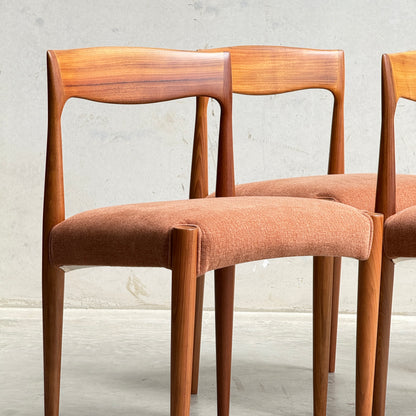 A set of four fully restored THB 'Milan' dining chairs from Rediscover, featuring reddish-brown upholstered seats, showcases classic Australian mid-century style against a light gray wall and concrete floor.