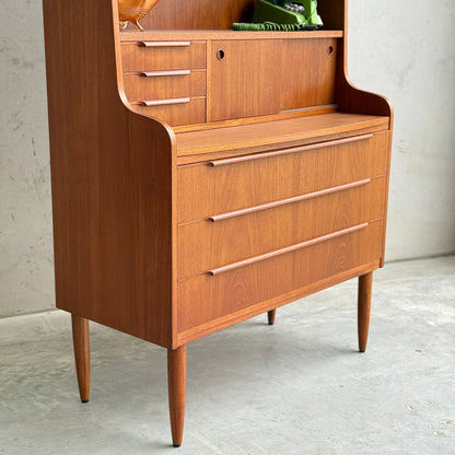 The Danish Teak Bureau Bookcase Secretary Desk by Erik Petersen for EP Møbler features mid-century modern design with curved edges, three wide drawers, an open shelf with small drawers and a cubby, set on four tapered legs.