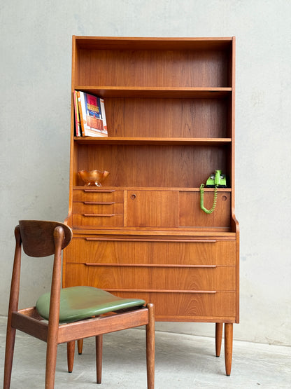 The Danish Teak Bureau Bookcase Secretary Desk by Erik Petersen for EP Møbler (Refine) features shelves, drawers, books, a green vintage telephone, glass bowl accents, and is paired with a matching wooden chair with a green cushion.