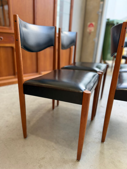 Parker Vintage Dining chairs with black leather seats and wooden frames on a light-colored floor.