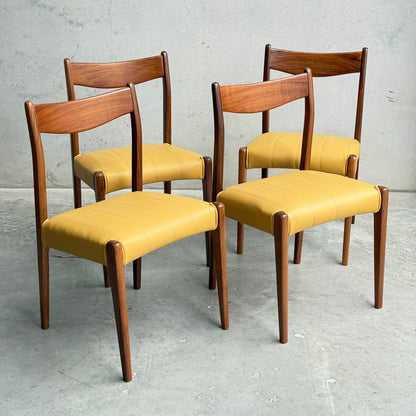 A set of four fully restored THB 'Stockholm' dining chairs (Rediscover) with Tasmanian blackwood frames and yellow upholstery are arranged on a concrete floor against a plain gray wall.