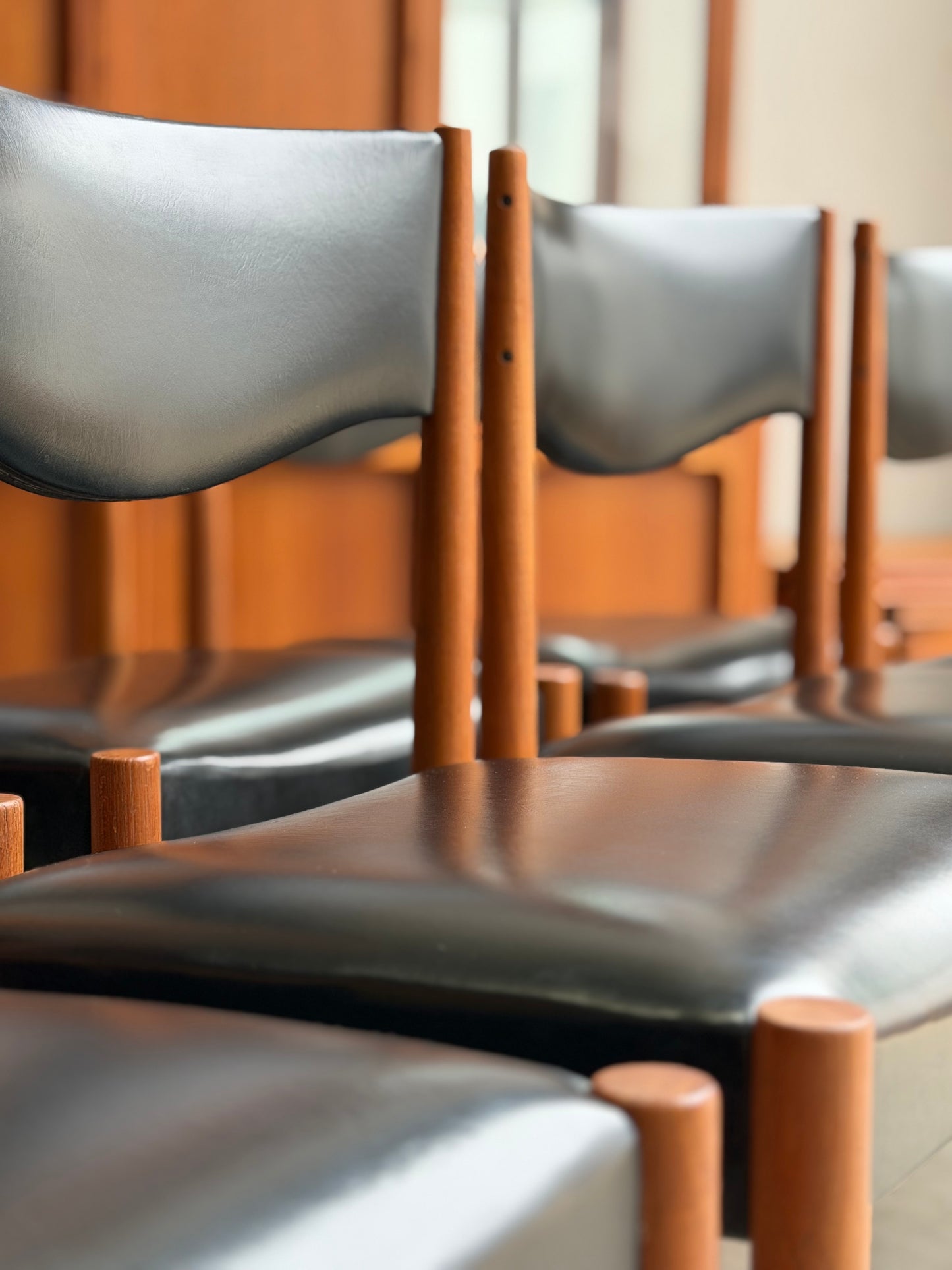 Close-up of wooden chairs with leather seats in a row.