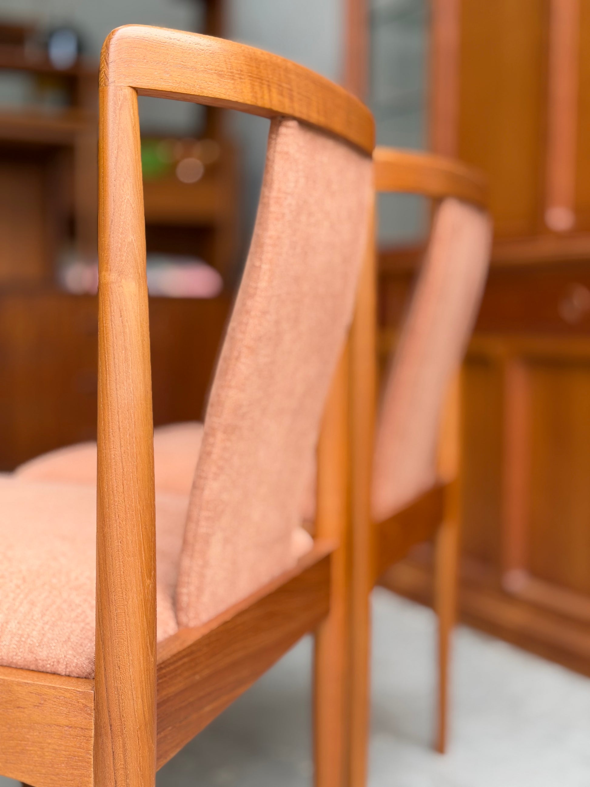 Four fully restored Parker T-Back Number 88 dining chairs in terracotta upholstery are displayed indoors beside a matching cabinet—a stunning showcase of Rediscover’s craftsmanship.
