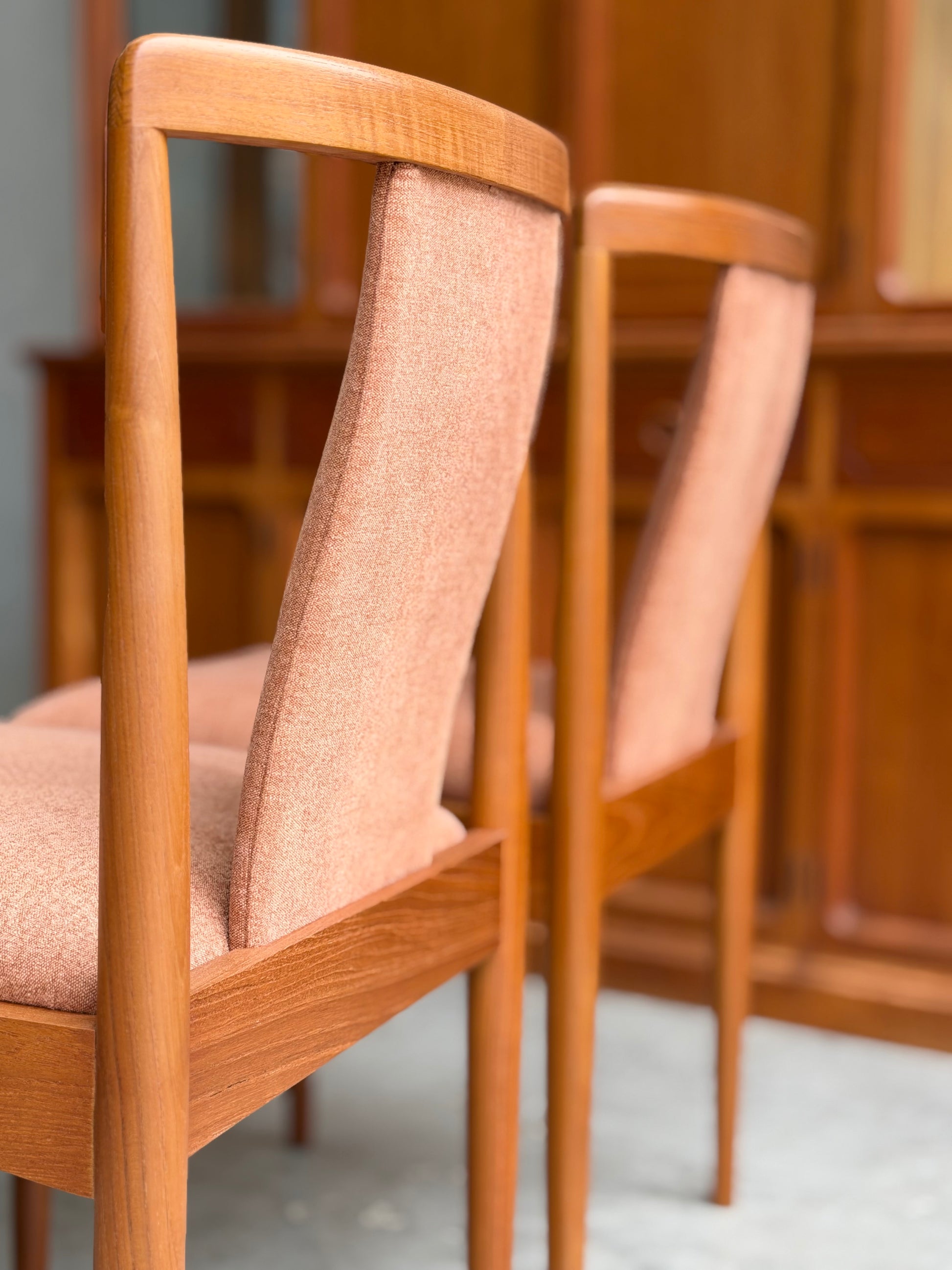Two fully restored Parker T-Back Number 88 dining chairs in terracotta from a set of 4 (Rediscover) are placed side by side, with matching wooden furniture softly blurred in the background.