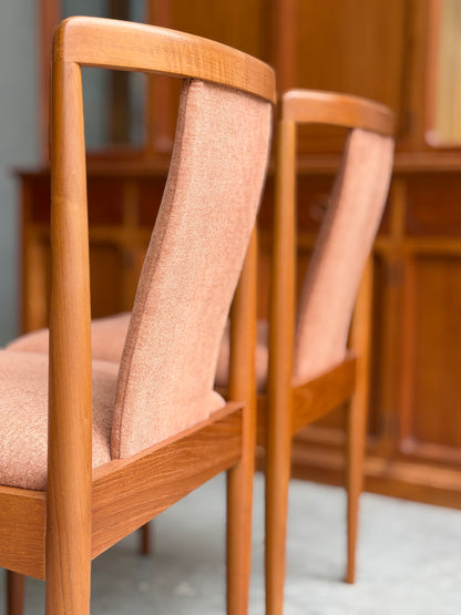 Two fully restored Parker T-Back Number 88 dining chairs in terracotta from a set of 4 (Rediscover) are placed side by side, with matching wooden furniture softly blurred in the background.