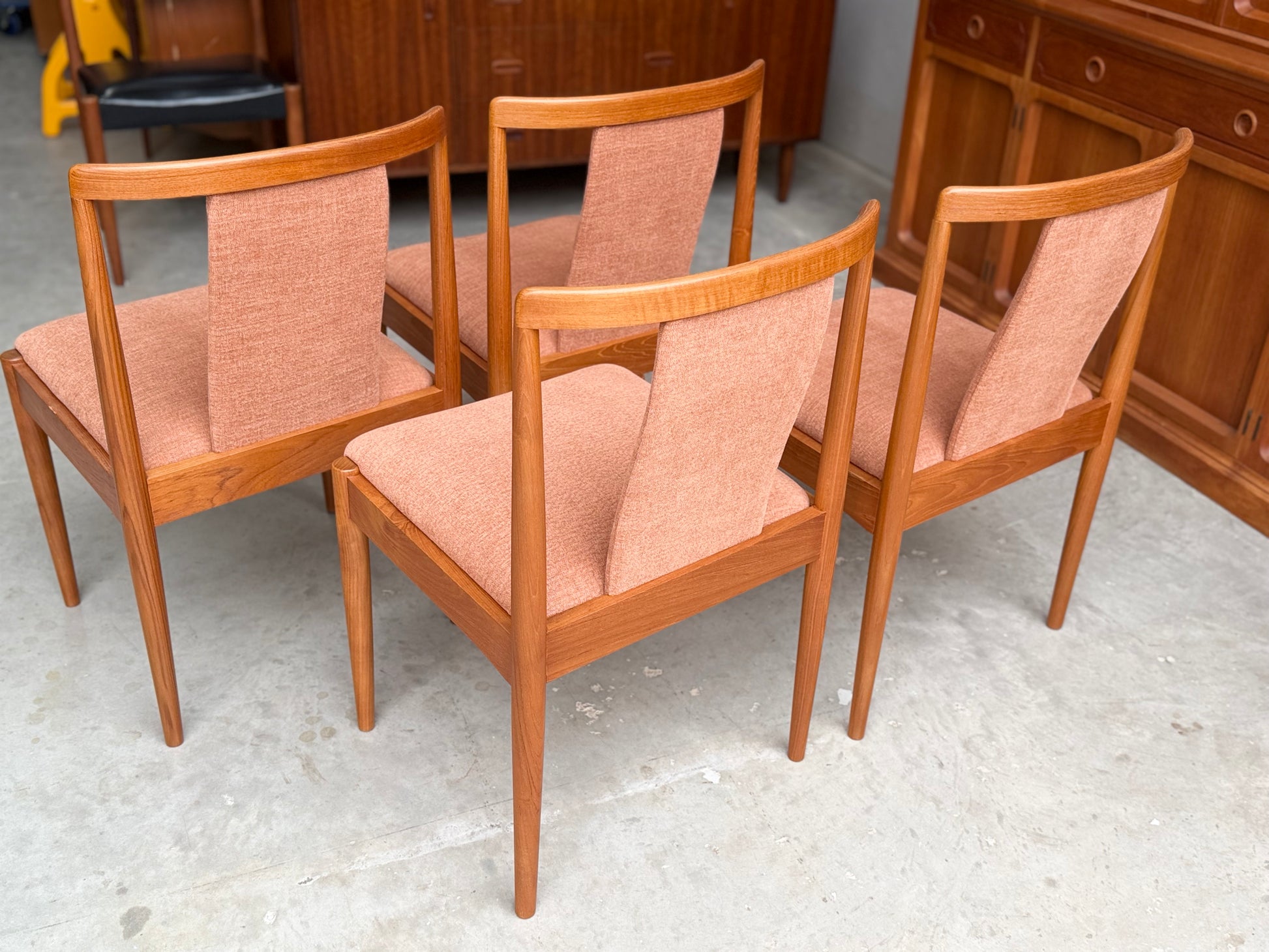 Four fully restored Parker T-Back Number 88 dining chairs, set of 4 in terracotta upholstery, are displayed on a concrete floor amid matching mid-century modern wooden furniture.