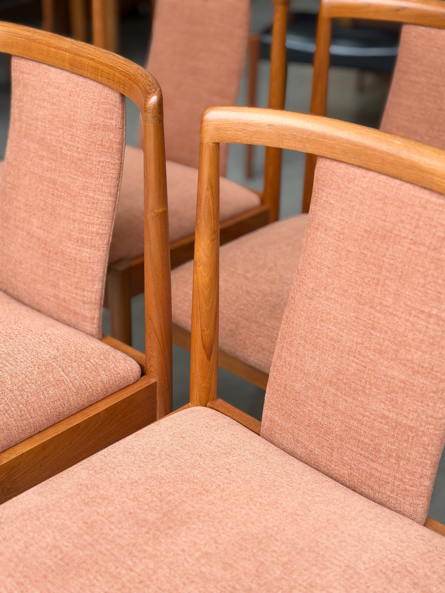 A set of four fully restored Parker T-Back Number 88 dining chairs in terracotta from Rediscover are arranged together indoors, highlighting their curved wooden armrests and textured upholstered seats and backs.