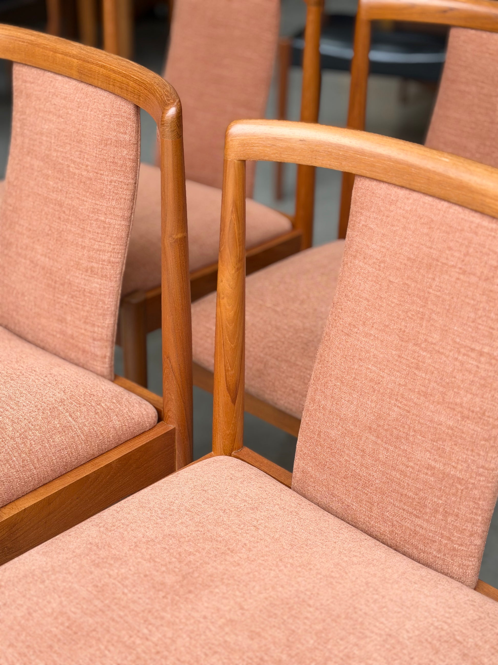 A set of four fully restored Parker T-Back Number 88 dining chairs in terracotta from Rediscover are arranged together indoors, highlighting their curved wooden armrests and textured upholstered seats and backs.