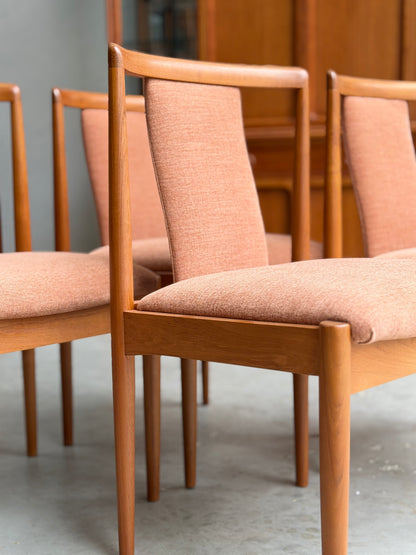 Four fully restored Parker T-Back Number 88 dining chairs in terracotta upholstery are arranged on a concrete floor, with wooden furniture visible in the background.