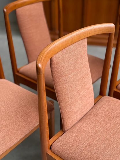 A set of four fully restored Parker T-Back Number 88 dining chairs in terracotta upholstery is displayed on a gray floor, surrounded by other mid-century modern wooden furniture.