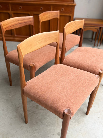 A set of fully restored THB 'Milan' Dining Chairs (set of 4) with curved backs and light brown seats are arranged on a concrete floor, complemented by a wooden sideboard and nested tables in the background.