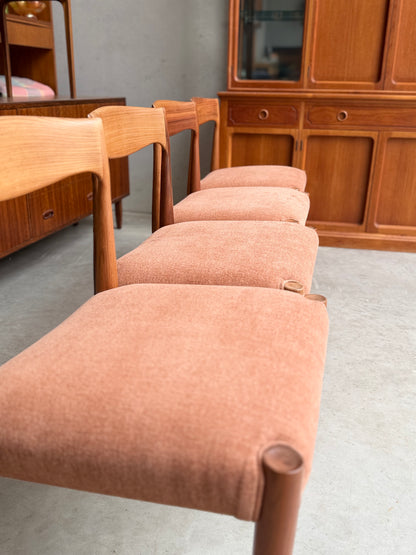 A set of four fully restored THB 'Milan' dining chairs (Rediscover) with light brown upholstered seats and wooden frames are arranged in a row, with a wooden cabinet and other furniture visible in the background on a concrete floor.