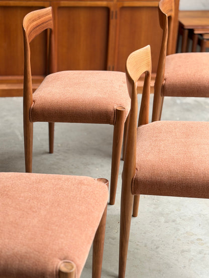 The Fully Restored THB 'Milan' Dining Chairs Set of 4 (Rediscover) feature light brown upholstered seats and backs, arranged on a concrete floor with a wooden cabinet behind, highlighting their timeless mid-century craftsmanship.