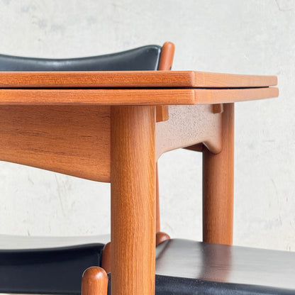 Close-up of the Fully Restored Parker 140 Square Extension Table (Rediscover) with rounded legs and a matching chair with black seat and backrest, set against a light textured background.