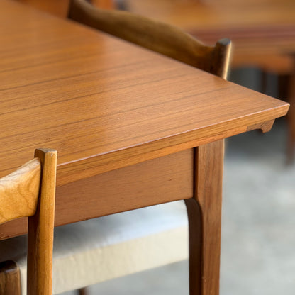 Close-up of the Fler 64 Rectangular Extension Table (Refine), inspired by vintage Australian design, showcasing its smooth grain, angled edges, and matching chairs with curved backs and light cushioned seats.