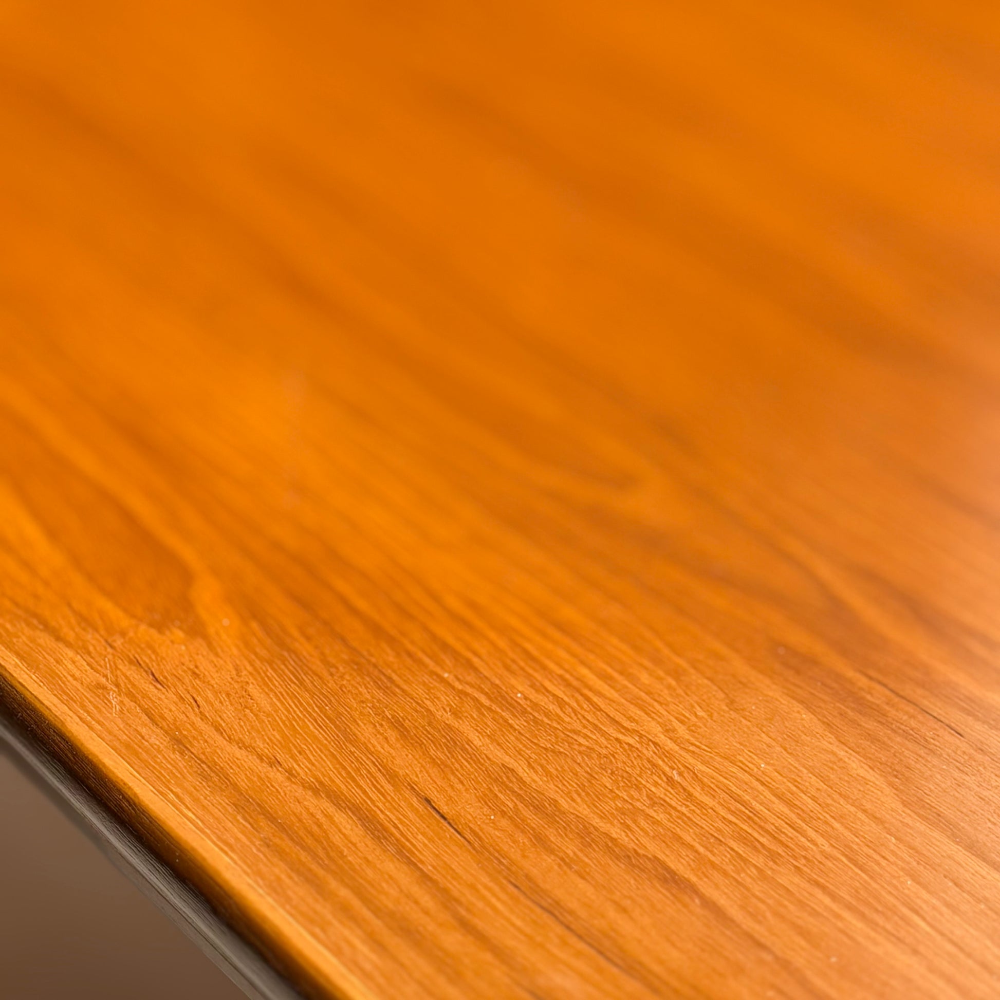 Close-up of the Mid Century Teak Danish Style Coffee Table – Circa 1970s (Revive), highlighting its warm orange-brown tone, natural grain, and smooth polished finish that reflects light—an elegant example of vintage craftsmanship.