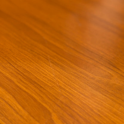 A close-up of the Mid Century Teak Danish Style Coffee Table – Circa 1970s (Revive), showcasing its smooth, polished teak surface with warm brown tones and visible wood grain inspired by classic Scandinavian design.