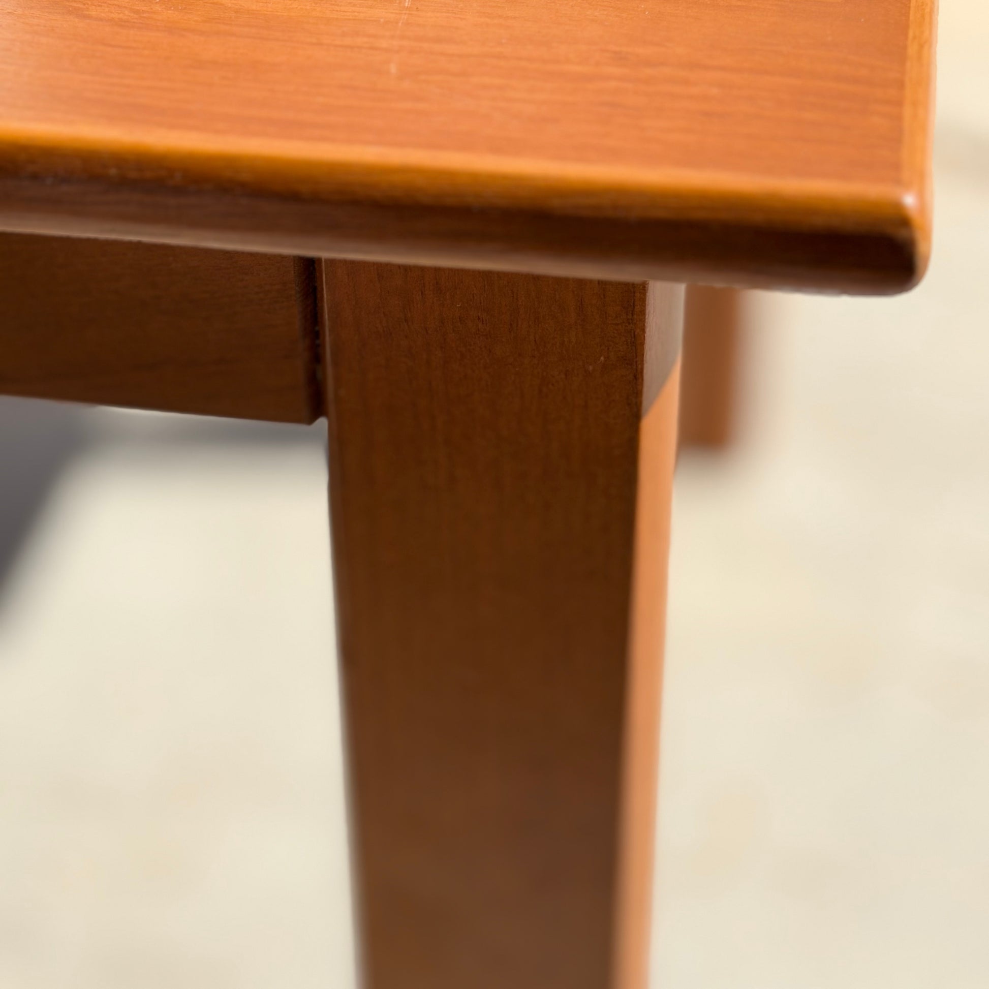 Close-up of a Mid Century Teak Danish Style Coffee Table – Circa 1970s (Revive), focusing on the smooth-finished corner, leg, and underside. The blurred background highlights its vintage Scandinavian design.